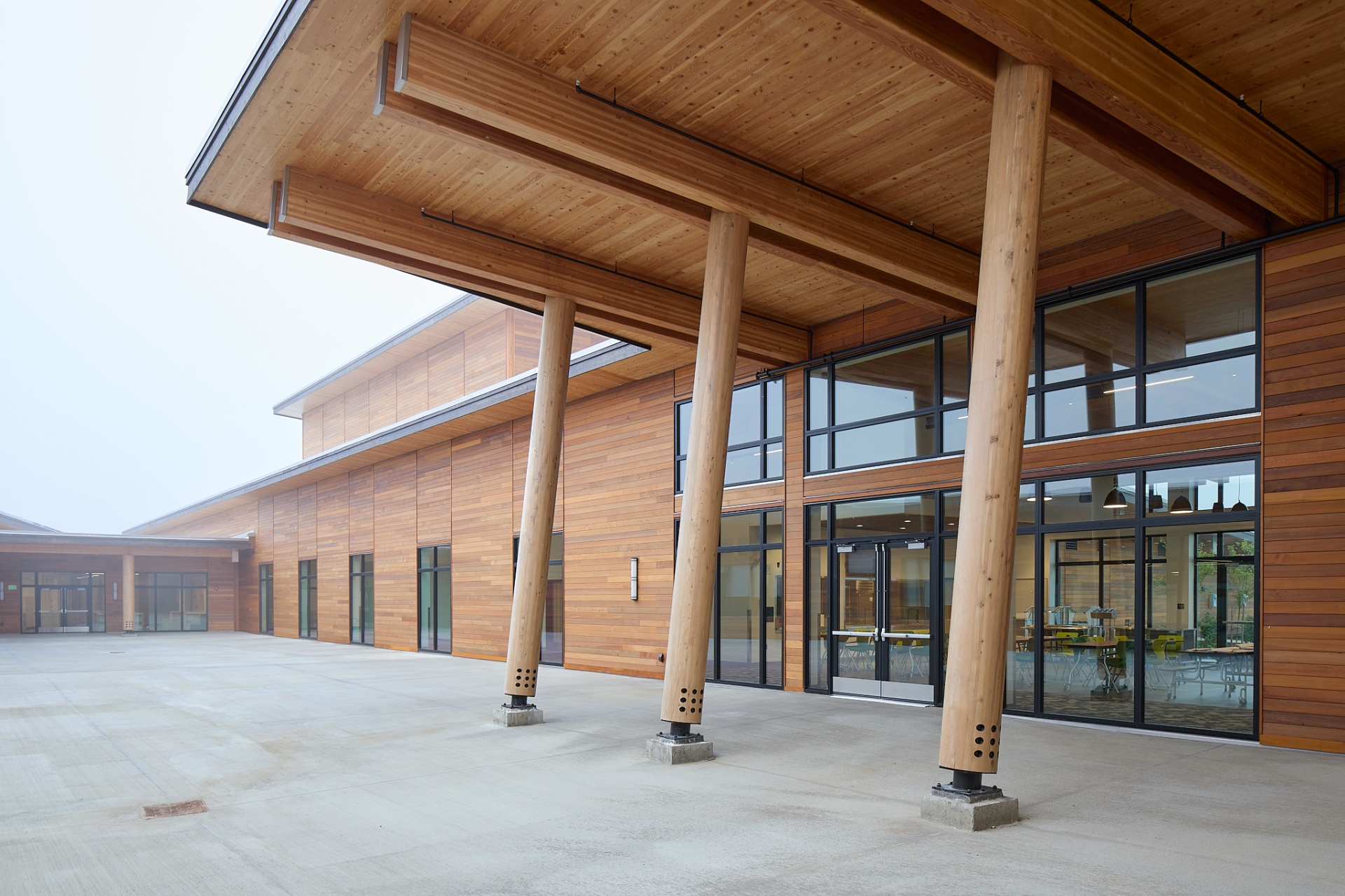 Covered exterior walkway with mass timber roof and log columns