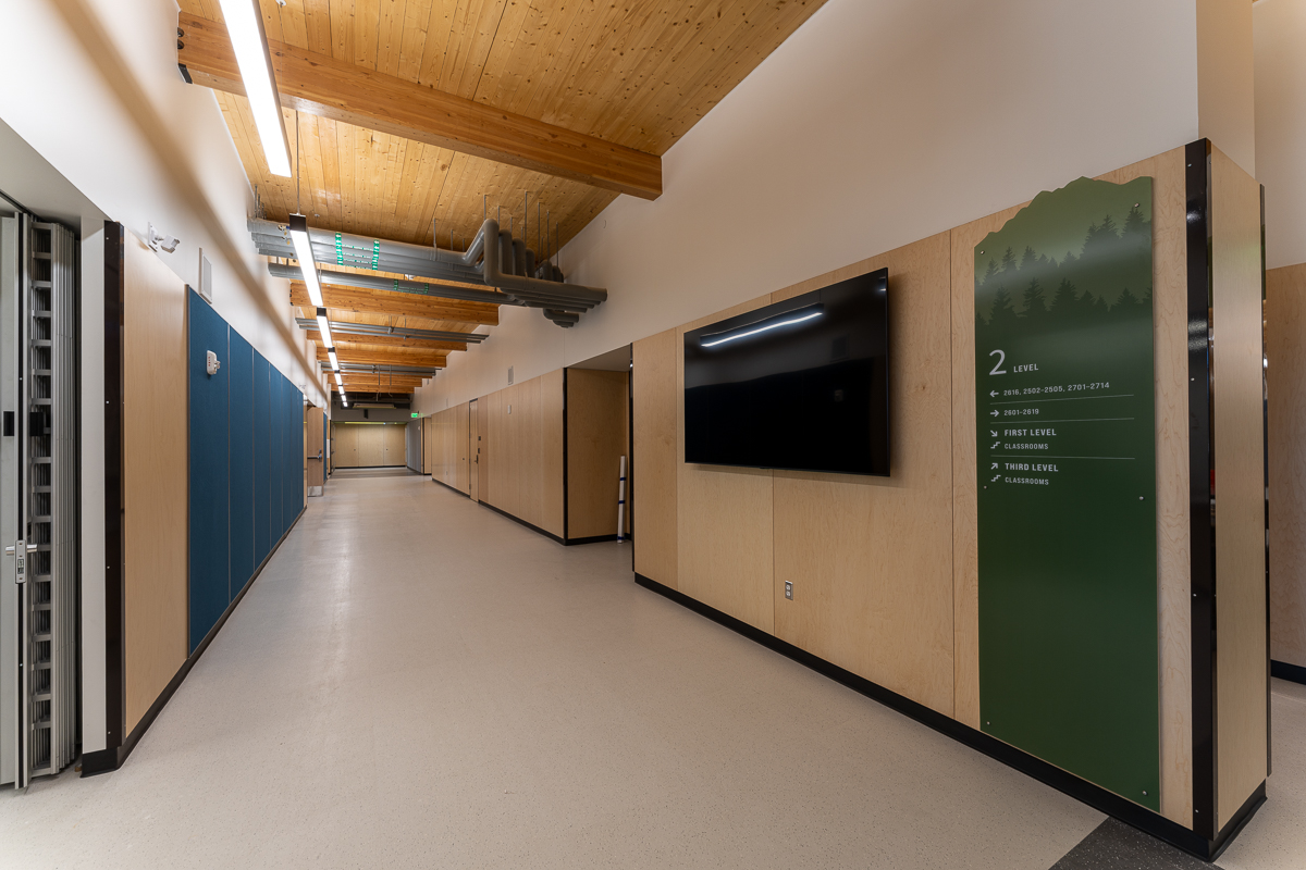 Lockered student corridor with wayfinding graphics under timber ceiling